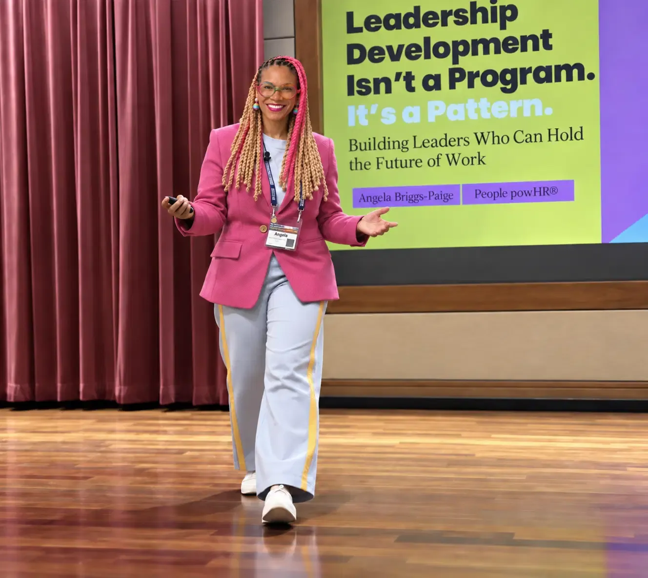 Angela Briggs-Paige speaking on stage with a clicker beside a slide about leadership development